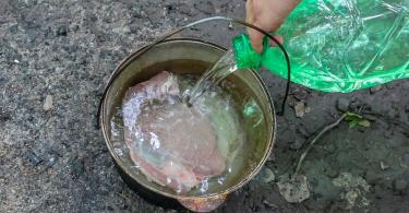 Σούπα σε μια κατσαρόλα από χυτοσίδηρο πάνω από μια φωτιά.  Δρύινα βαρέλια.  Κοτόσουπα